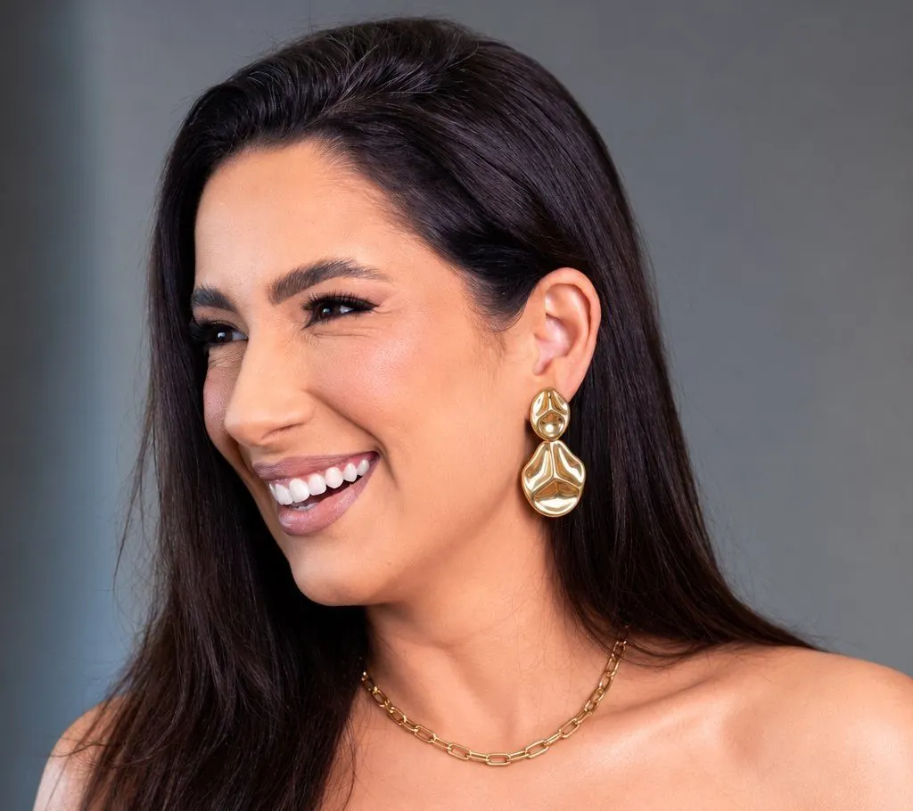 Ju Manzalli sorrindo, usando brinco orgânico dourado e corrente da Manzalli
